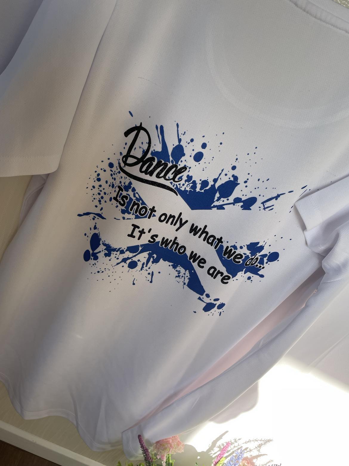 a photo of a white tshrt with Dance - it's not only what we do; it's who we are on it in a blue and black splash design